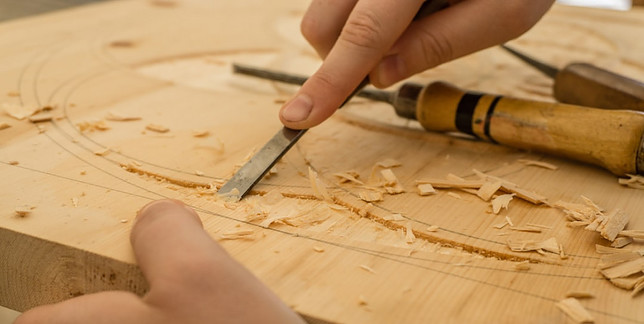 A pair of hands working on wood with a tool