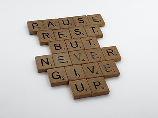 Image shows letter tiles organized to spell "Pause rest but never give up"