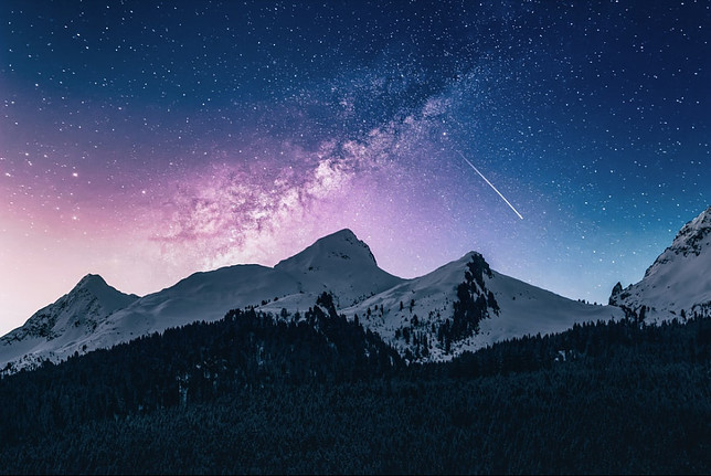 Image shows a snow capped mountin beneat starry night sky