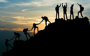 Image shows the silhouette of nine people climbing up the silhouette of a mountian in the foreground with a twilight sky in the background