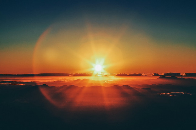 Image shows a sun shining over the clouds with a slight orange light