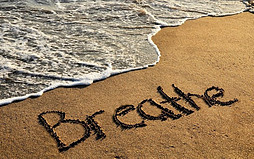 Image shows a beach with the word "Breathe" written on it as a wave ebbs away