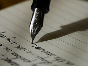 Image shows a fountain pen writing on a lined page